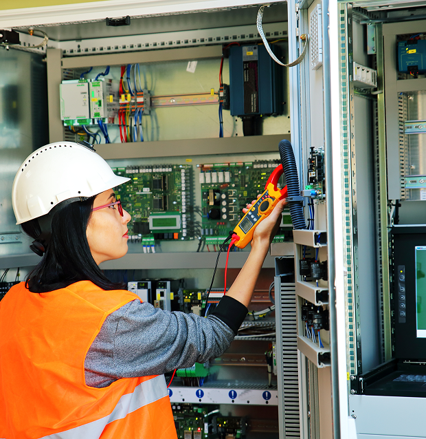 Worker using multimeter on control panel