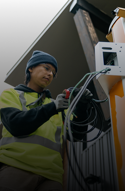 Worker installing electrical equipment outdoors