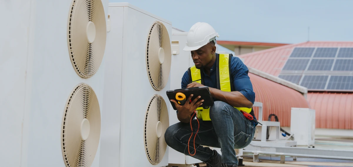 Worker with tablet examining AC equipment