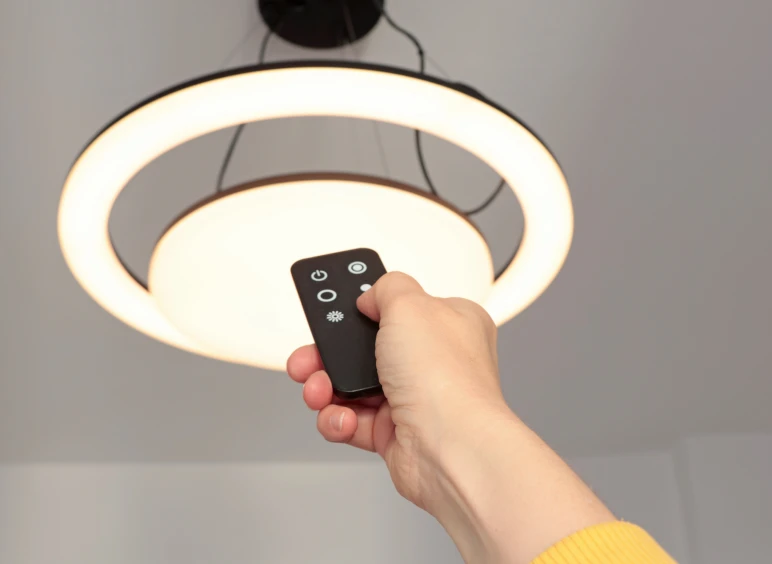 Hand holding remote for ceiling light