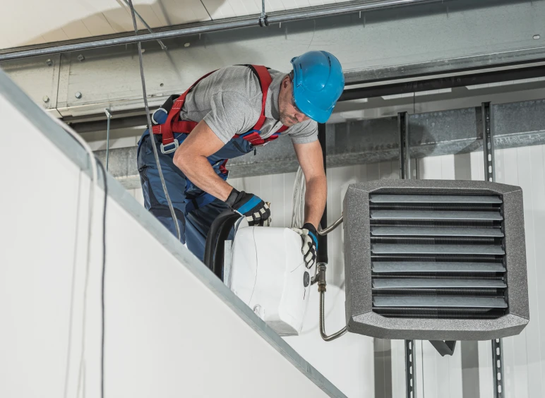 Technician fixing warehouse ventilation unit