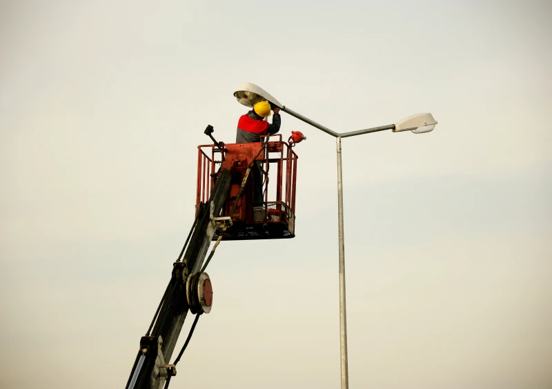 Worker fixing streetlight on lift
