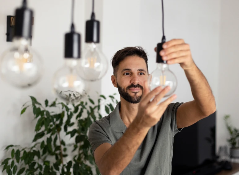 Man adjusting a hanging light bulb