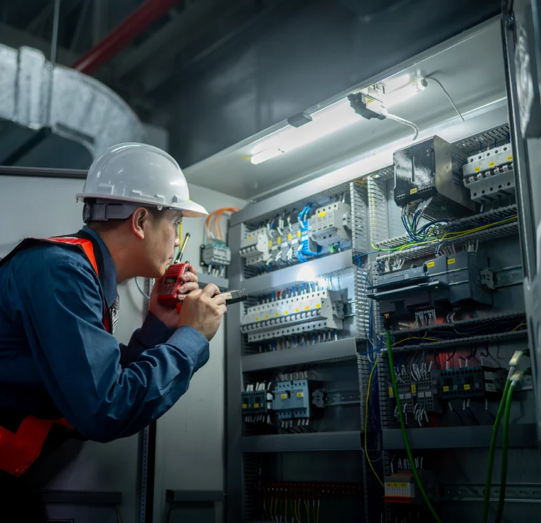Electrician inspecting control panel with flashlight.